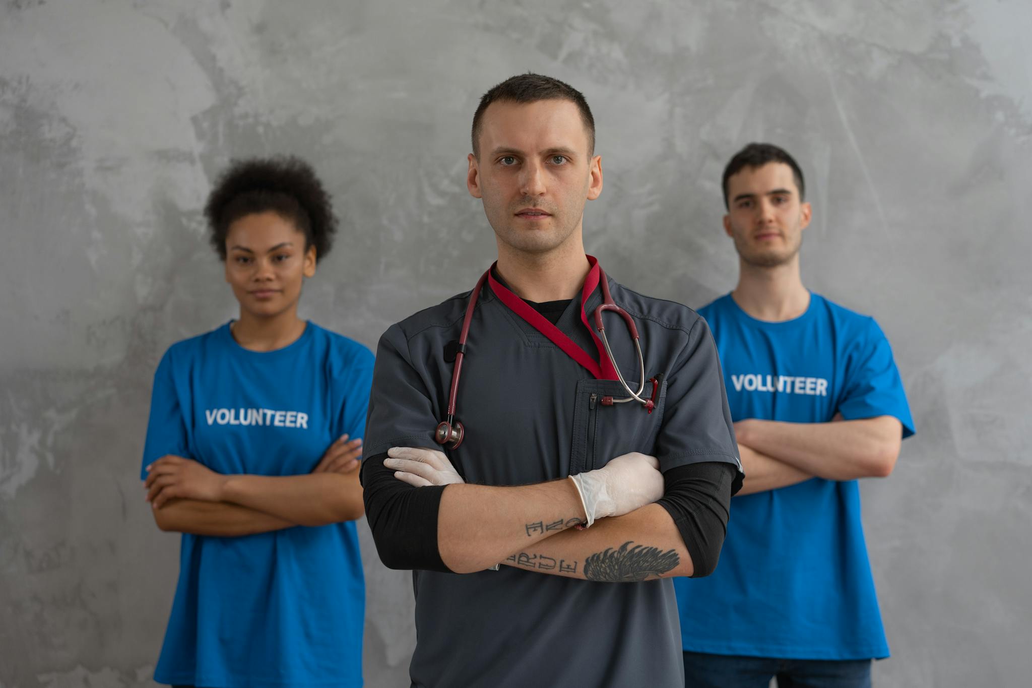Healthcare worker with stethoscope and volunteers standing in solidarity indoors.